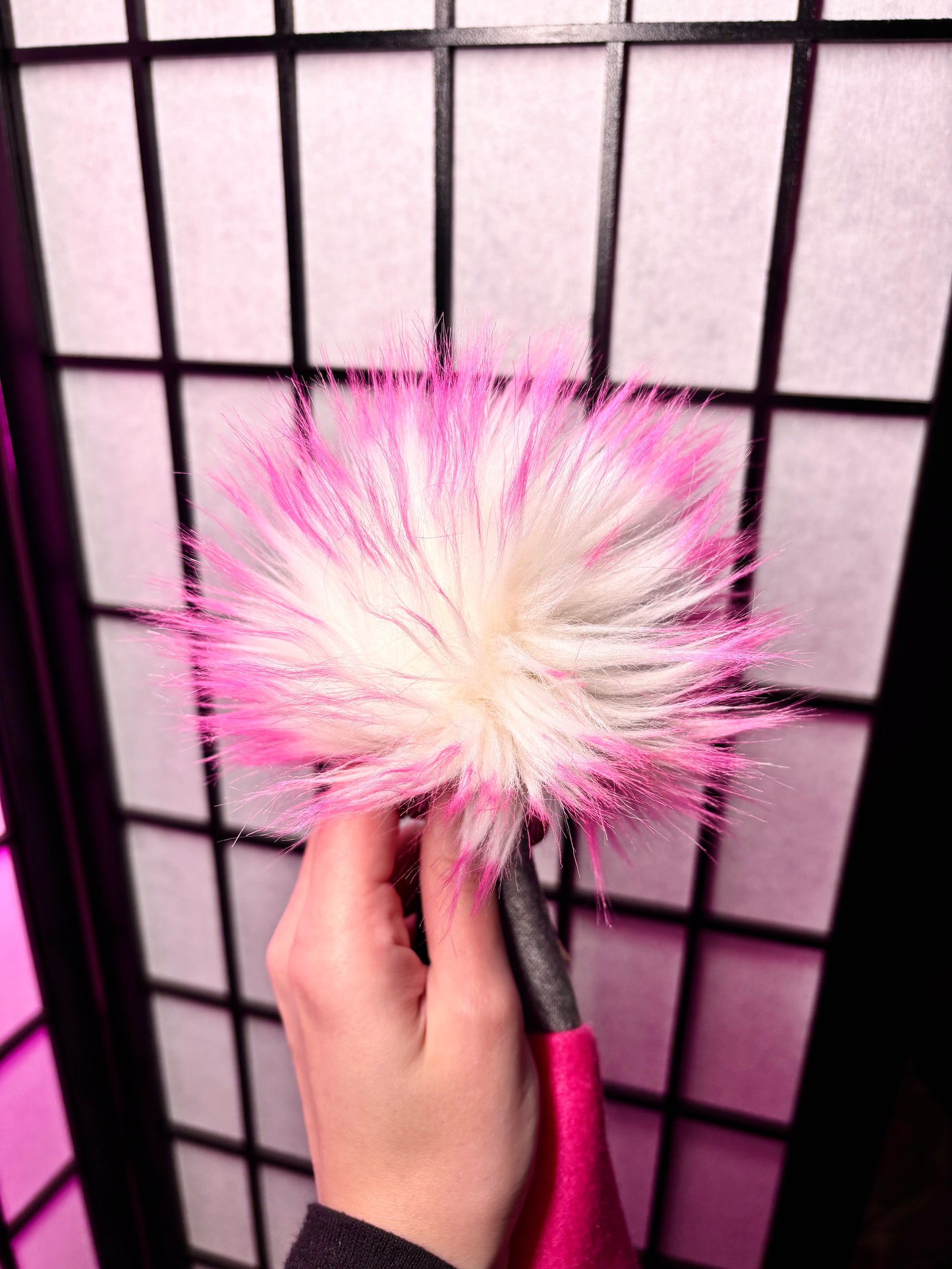 white pom with pink tips faux fur. photographed with flash and a grid background.