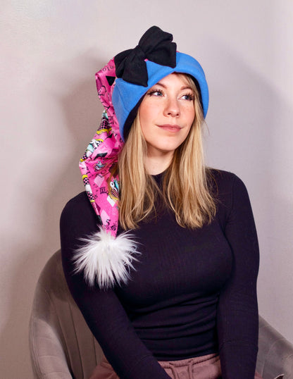 Person wearing a colorful headscarf with a large black bow and pink patterned Santa Hat. Inspired by Alice in Wonderland.