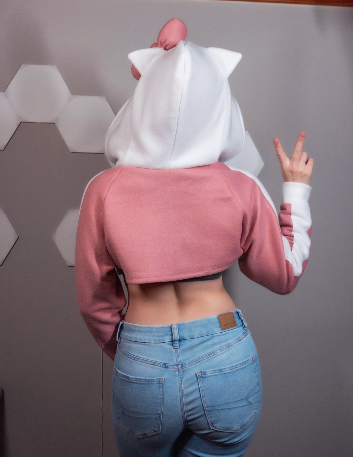 Girl wearing a handmade cosplay shrug inspired by Hello Kitty. It is pink and white with Hello Kitty's face and bow on the hood. Very kawaii cute.