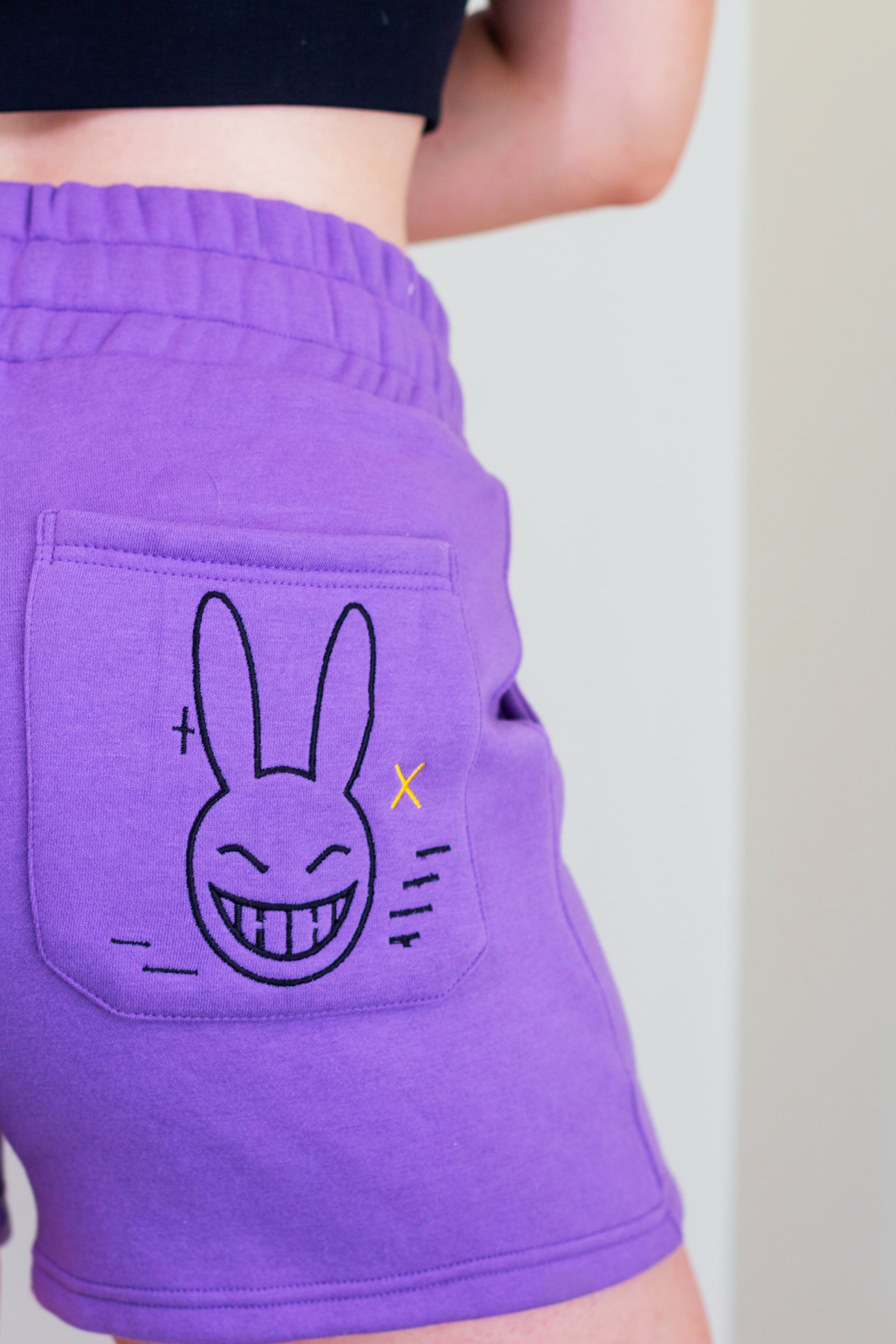 Purple shorts with a cartoon bunny design on the pocket against a neutral background. Inspired by Jax from the Amazing Digital Circus