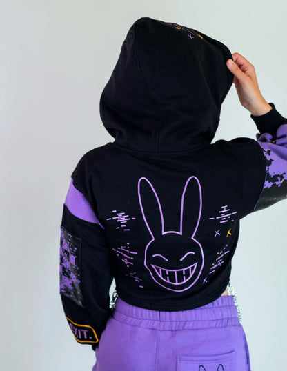 Person wearing a black hoodie with a purple bunny face design on the back, standing against a plain background.  Inspired by Jax from The Amazing Digital Circus TADC