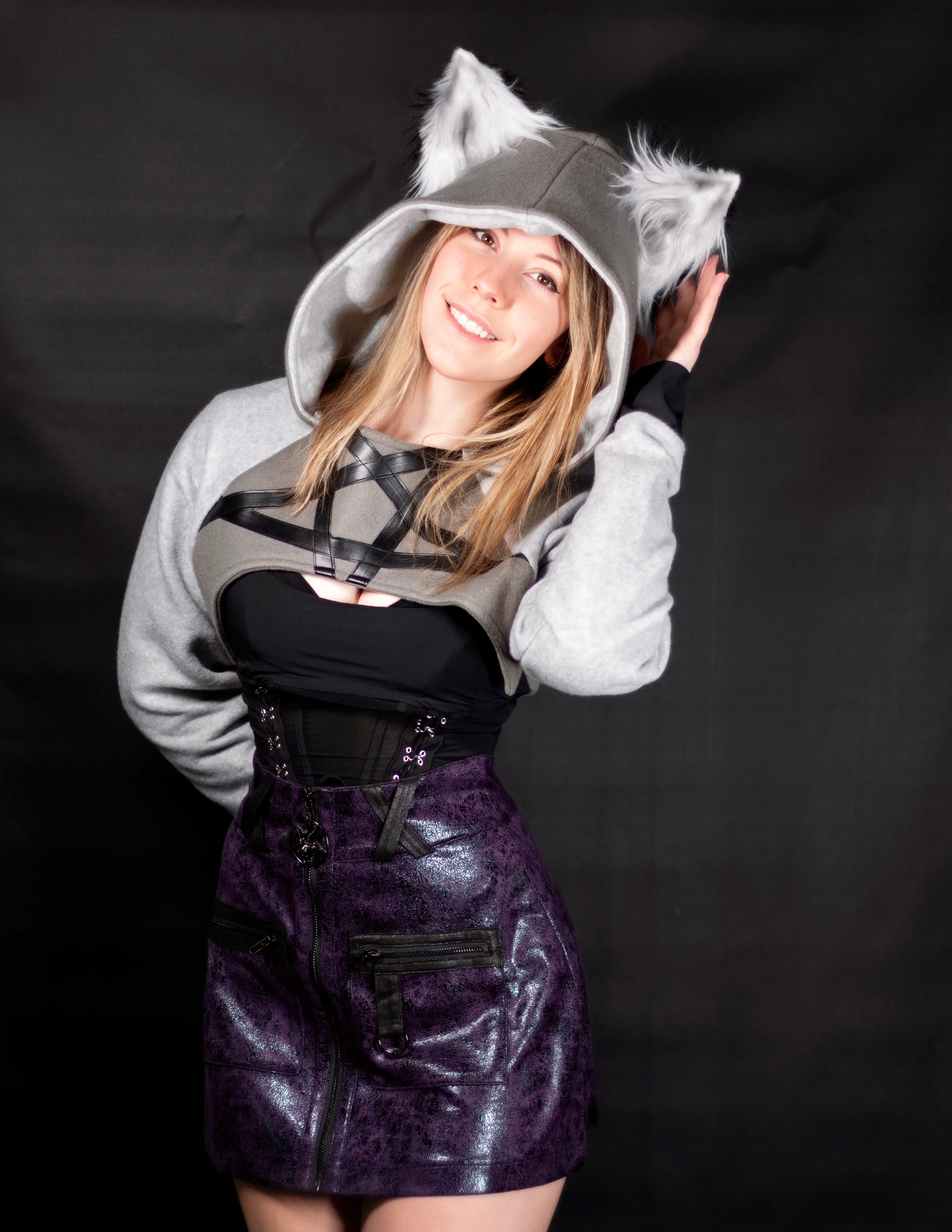 Person wearing a gray hoodie with wolf ears, black top, and purple skirt on a black background. Cropped Hoodie is inspired by Loona from Helluva Boss