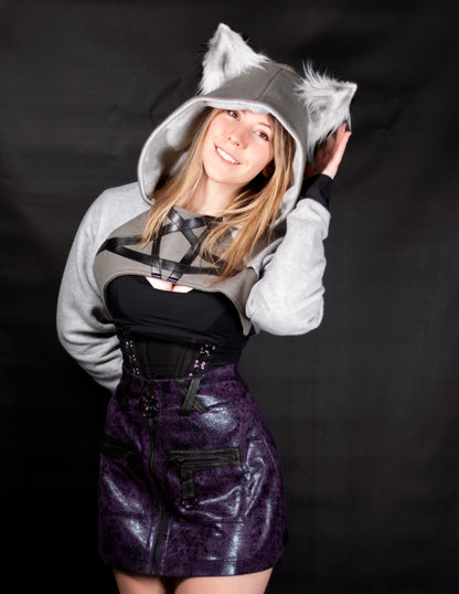 Person wearing a gray hoodie with wolf ears, black top, and purple skirt on a black background. Cropped Hoodie is inspired by Loona from Helluva Boss