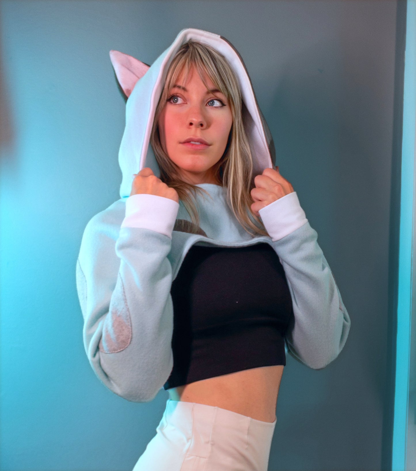 Person wearing a cosplay shrug inspired by Muffin from Bluey. It is light blue with multi-colored spots. 