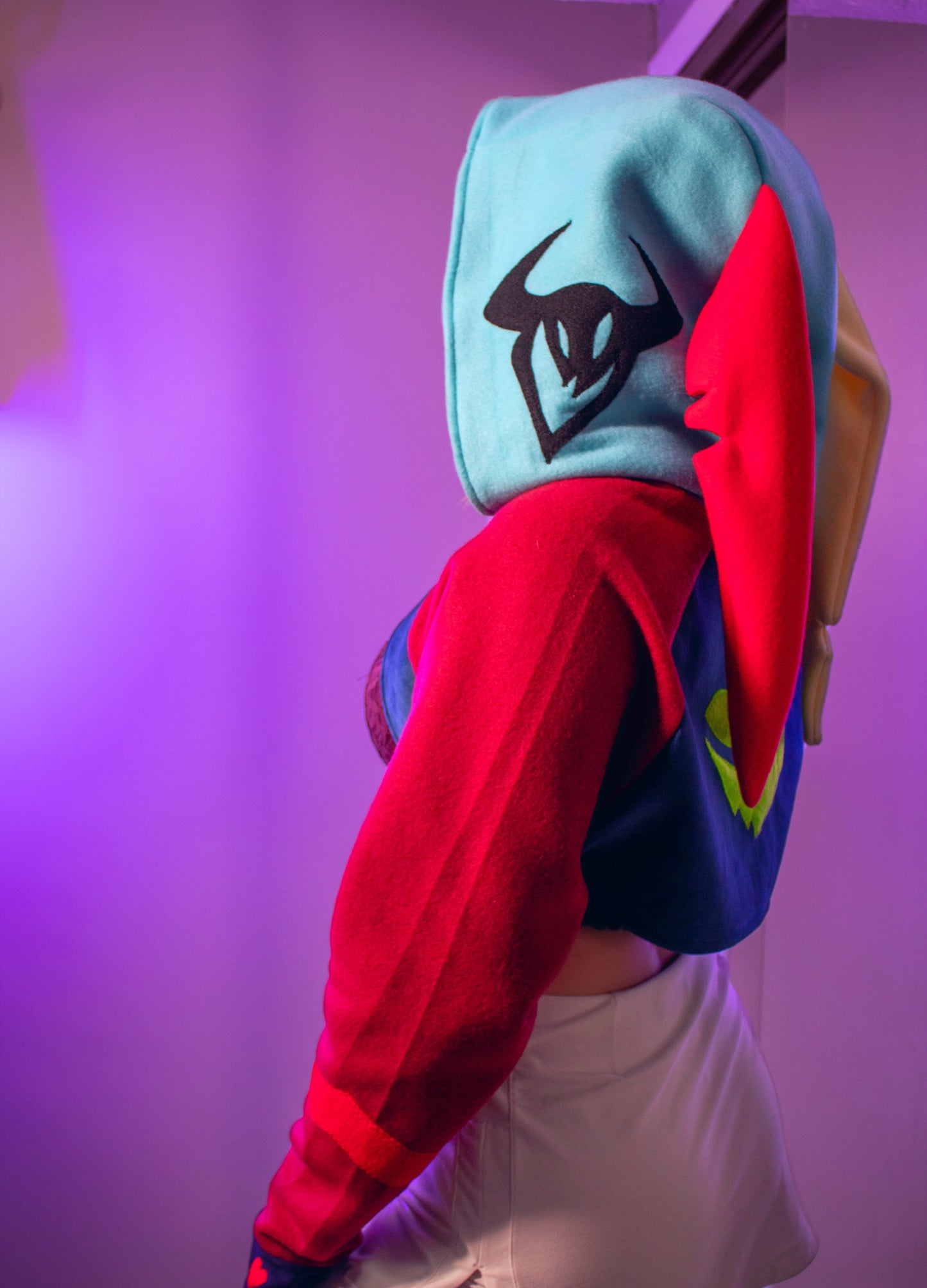 Asmodeus Cosplay cropped hoodie shrug inspired by Helluva Boss shown on a model with a purple background and matching outfit. showing his other faces on the side of the hood