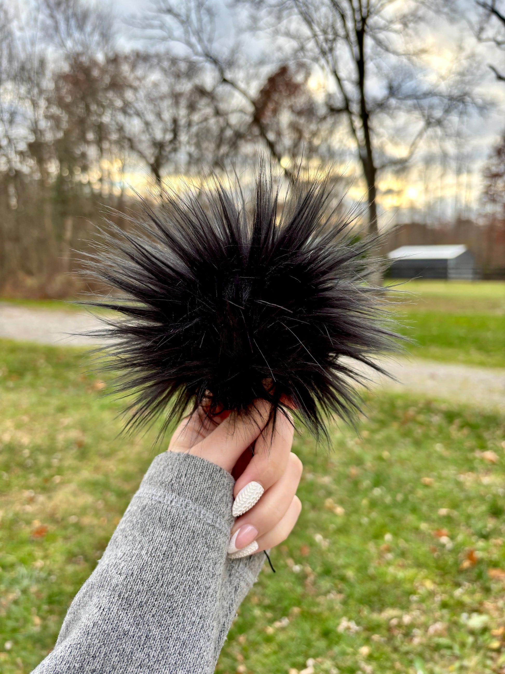 Hand holding a black faux fur pom