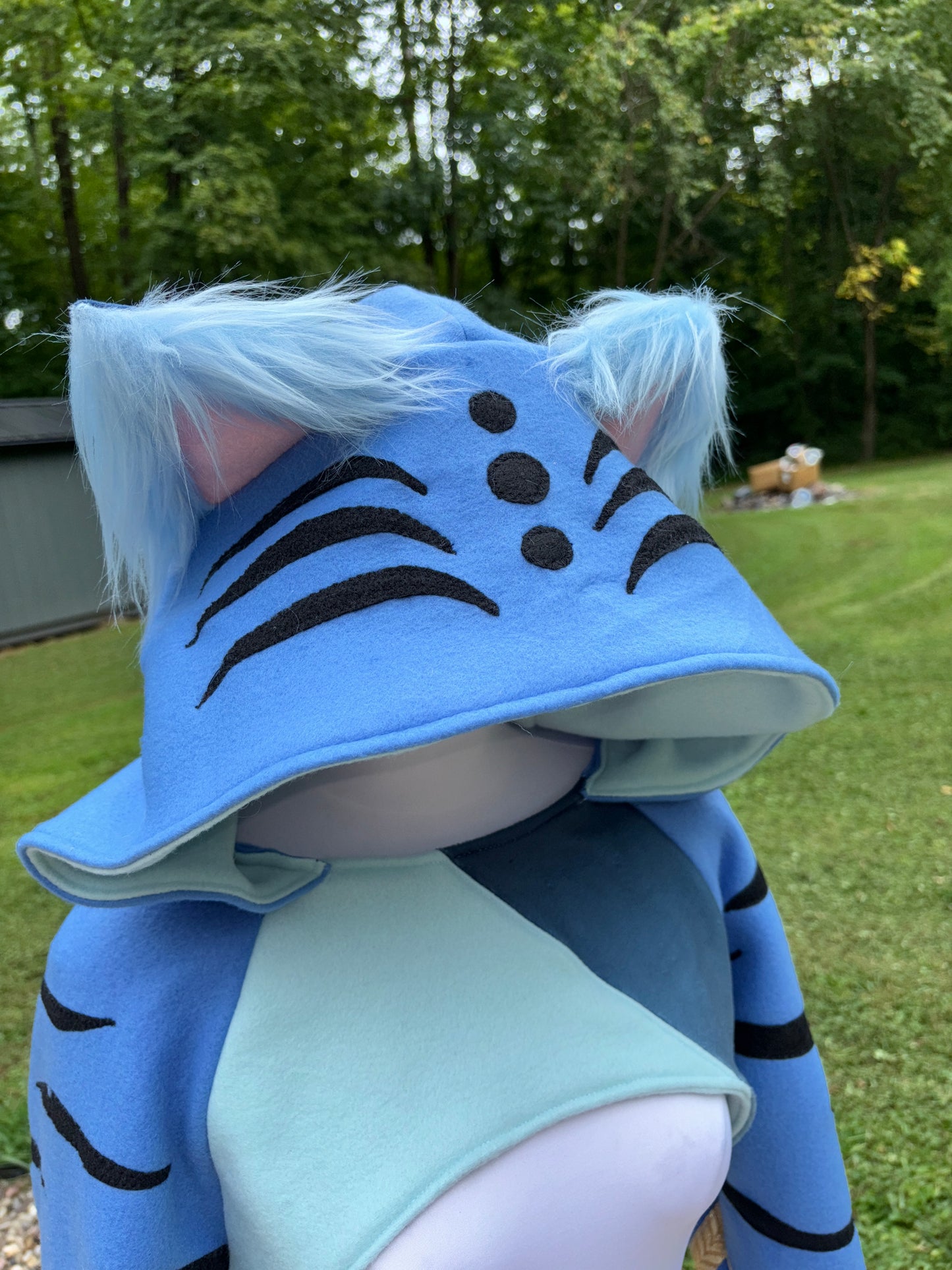 a cosplay shrug inspired by Derpy Tiger from Kpop Demon Hunters. It is different shade of blue with  character designs