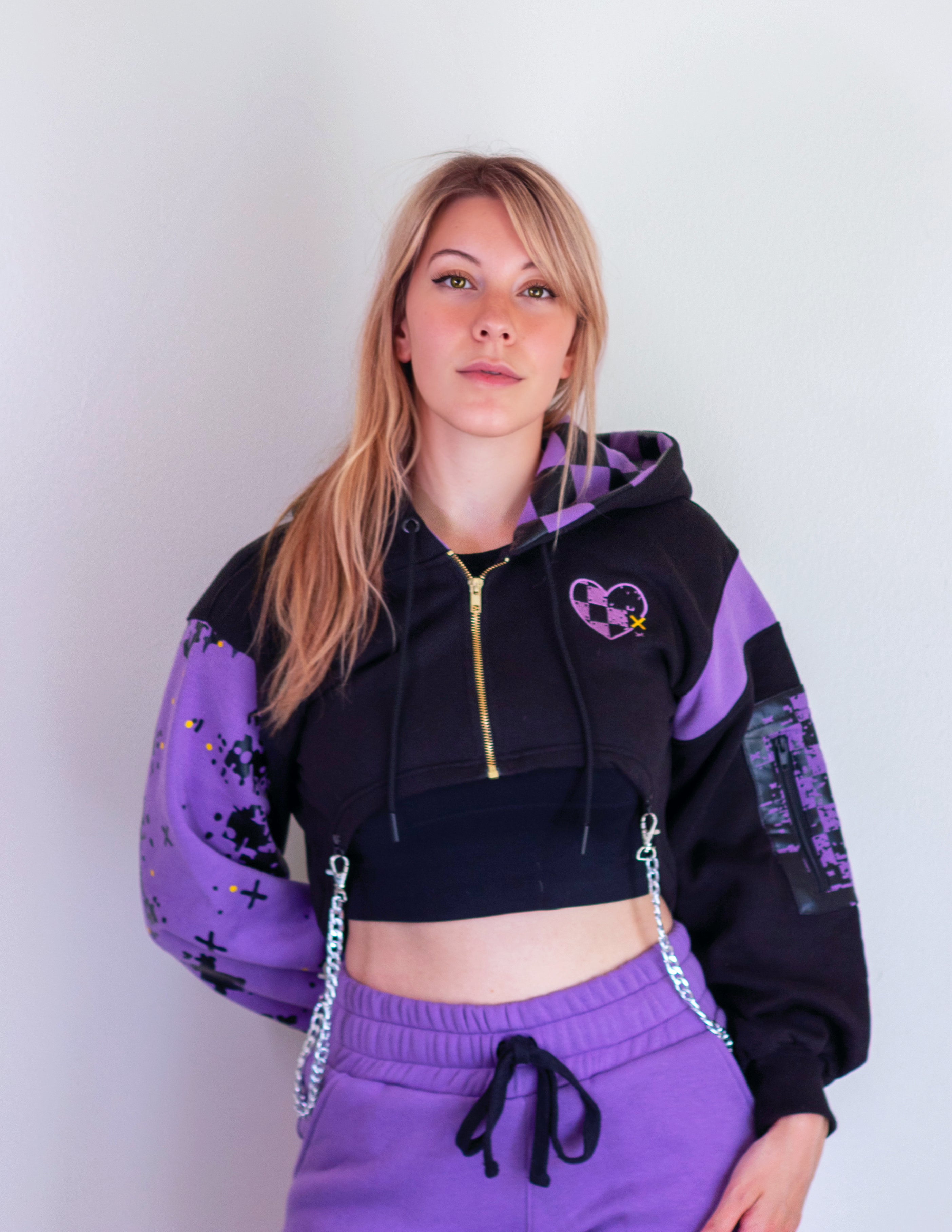 Person wearing a black and purple hoodie with a heart design on a plain background. Inspired by Jax from The Amazing Digital Circus TADC