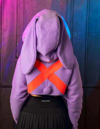 Person wearing a purple hoodie with bunny ears and an orange 'X' design, standing against a dark background. Inspired by Jax from the Amazing digital circus