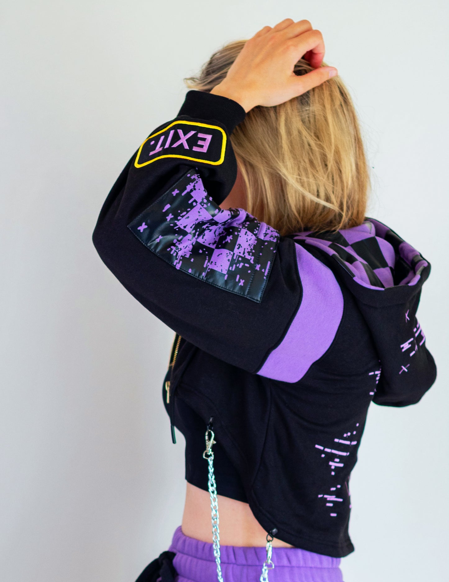 Person wearing a black and purple hoodie with digital design on sleeves against a white background.  Inspired by Jax from The Amazing Digital Circus TADC