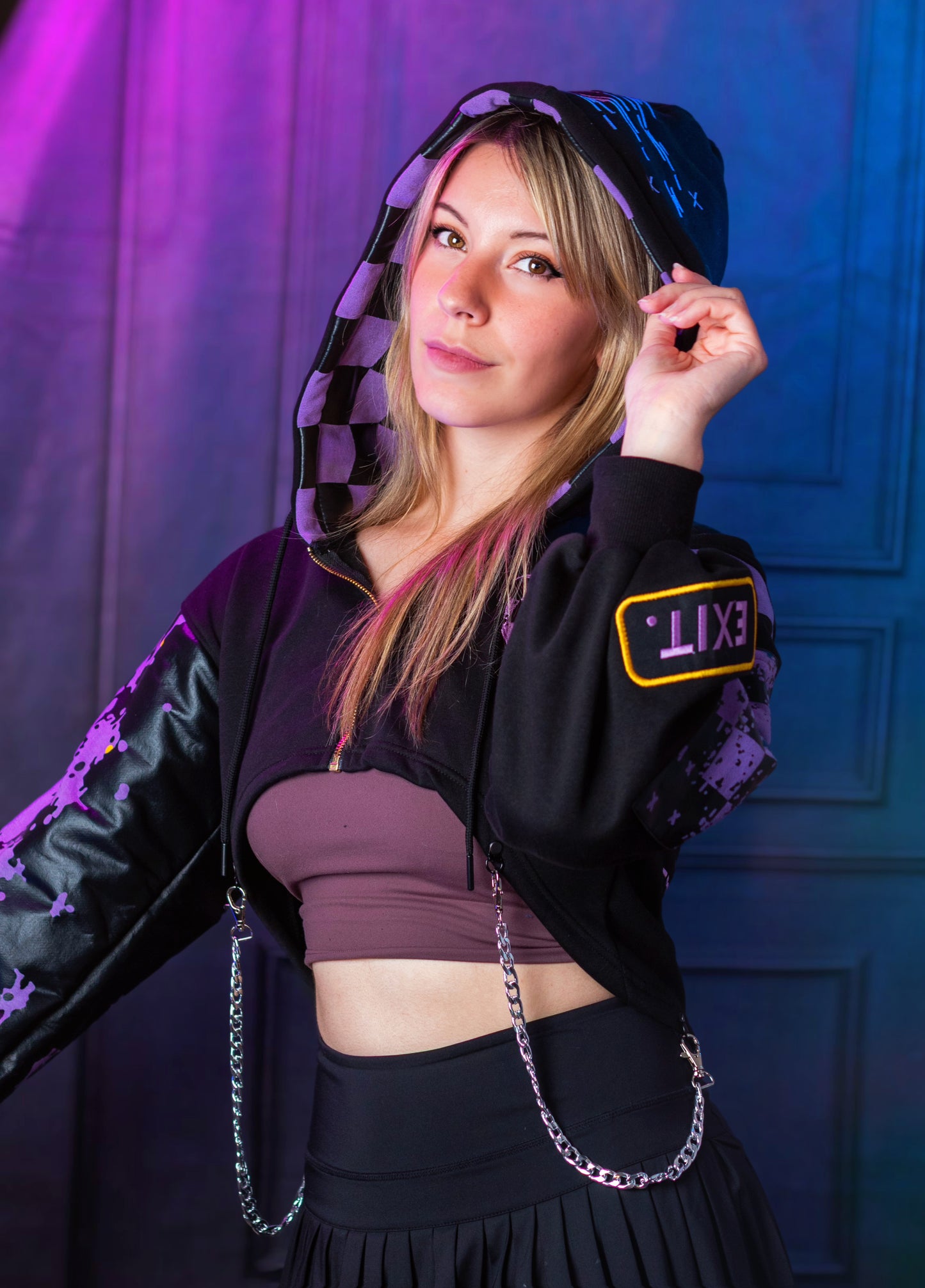 Woman wearing a black and purple outfit with a hood, standing against a blue and purple gradient background.  Inspired by Jax from the Amazing Digital Circus.
