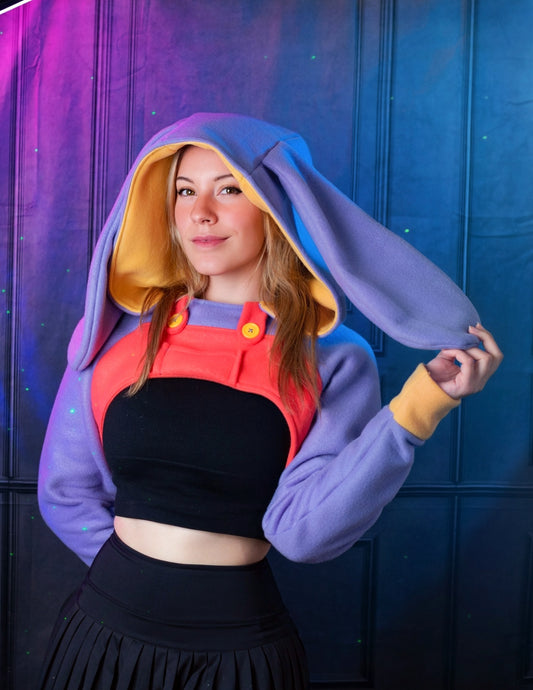 Person wearing a colorful hoodie with bunny ears against a blue and purple background. Inspired by Jax from the Amazing digital circus