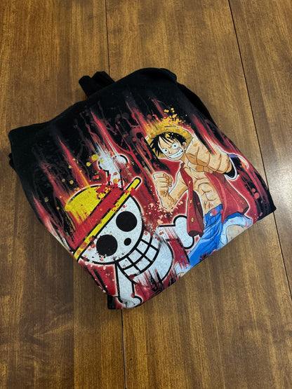 Black hoodie with a colorful graphic design on a wooden surface. Inspired by Luffy from One Piece. 