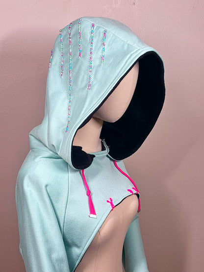 Light blue hoodie with black cuffs and pink drawstrings on a mannequin against a beige background. Inspired by  Vanellope von Schweetz from Disney's Wreck it Ralph. Perfect Cosplay Shrug.